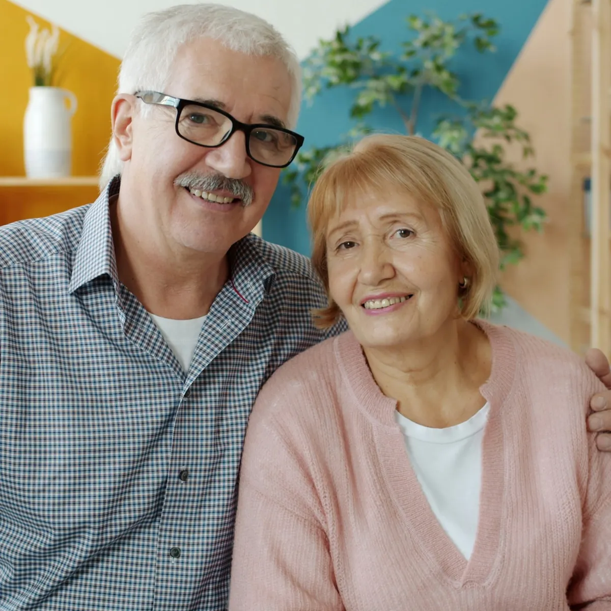 Pareja de adultos mayores sonriendo juntos en su living